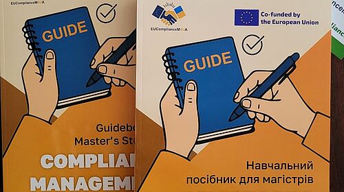 Compliance-Guidebook stärkt internationale Sichtbarkeit Englisches und ukrainisches Compliance-Guidebook liegen mit Flyern und Projektmaterialien auf einem Tisch.