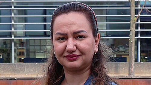 Rezvan Kakavand startet Promotion Porträt einer Frau im Freien vor einem modernen Hochschulgebäude. Sie trägt eine Jeansjacke und blickt in die Kamera.